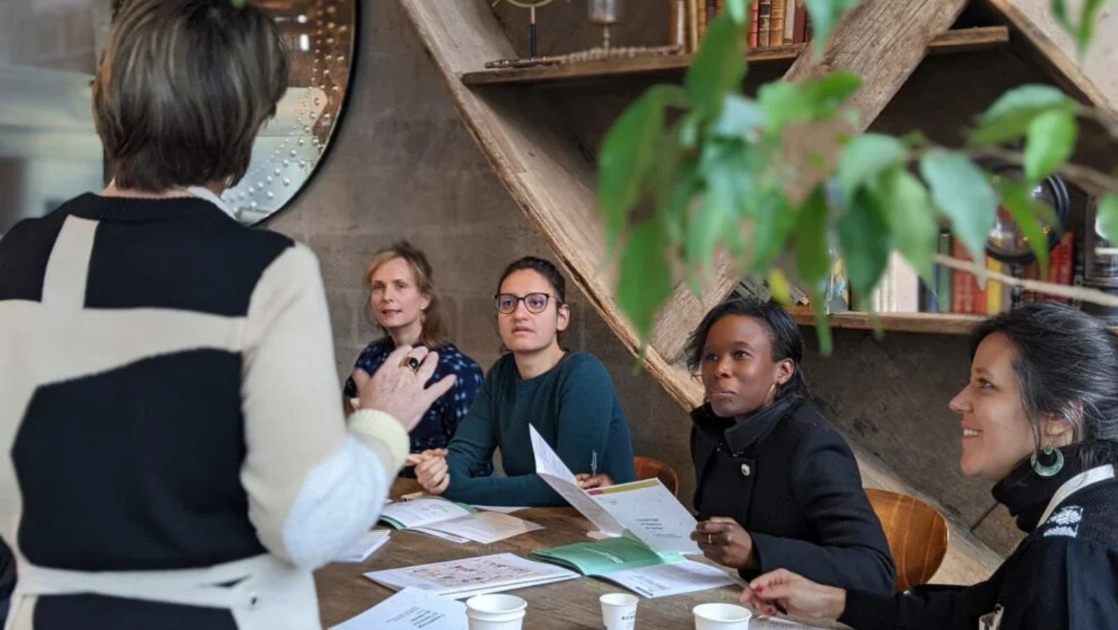 Un groupe d'adultes assis autour d'une table travaille ensemble et écoute quelqu'un parler
