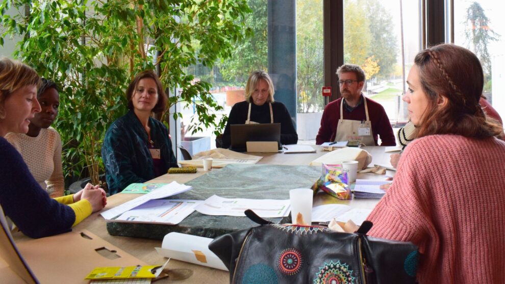 Un groupe d'adultes assis autour d'une table travaille ensemble et écoute quelqu'un parler