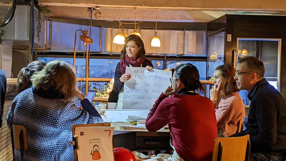 Un groupe d'adultes assis autour d'une table travaille ensemble et écoute quelqu'un parler