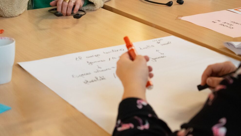 Gros plan d'une main en train d'écrire sur une large feuille de papier