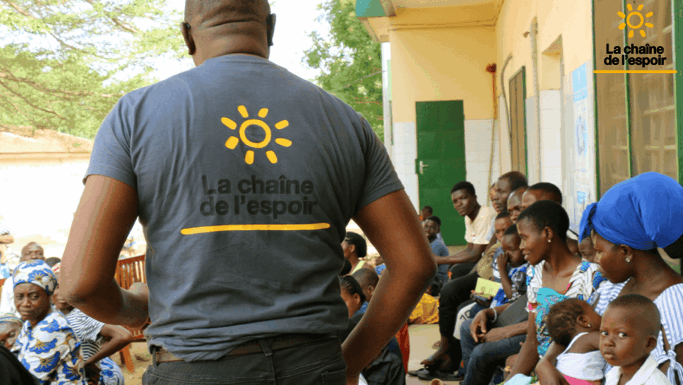 Groupe de parents et jeunes enfants face à une personne portant un tee-shirt "La chaine de l'espoir"