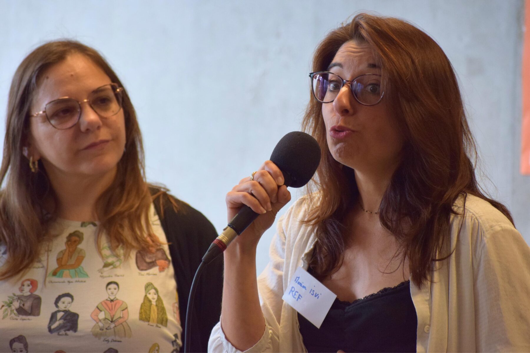 Une adulte parle debout sur une scène avec un micro