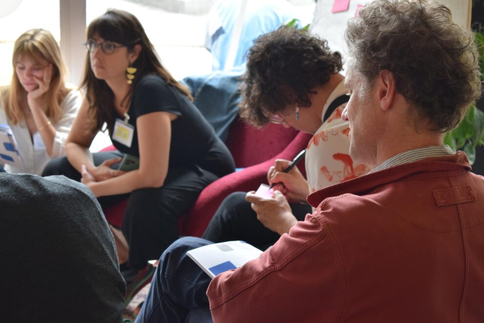 Un groupe d'adultes assis sur des canapés travaillent ensemble autour de post-its