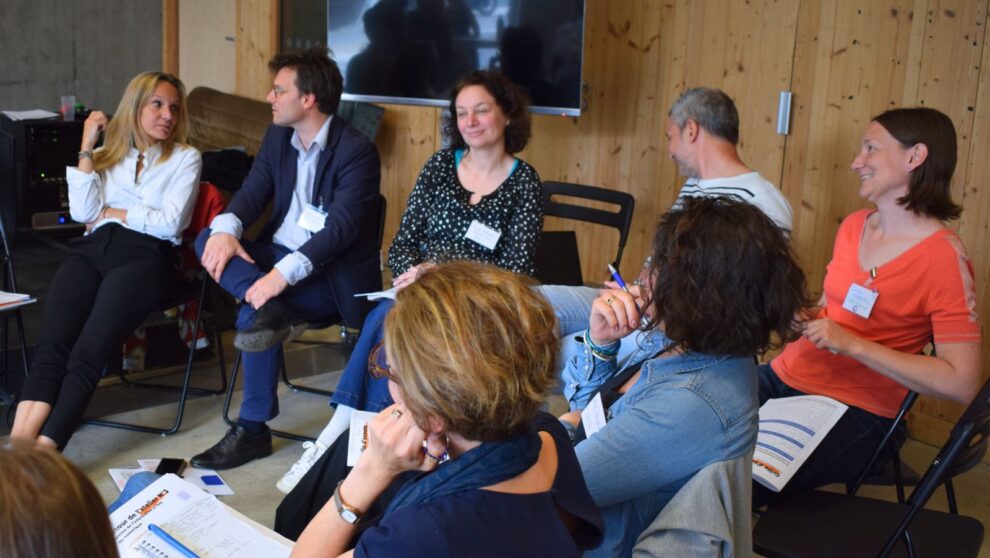 Groupe d'adultes assis-es en cercle, parlant et riant ensemble