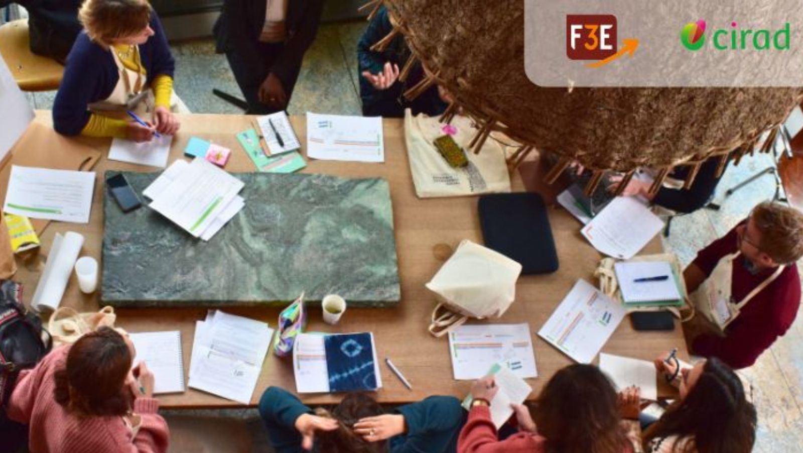 Un groupe d'adultes assis autour d'une table de travail avec les logos F3E et Cirad