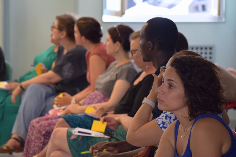 Un groupe d'adultes assis dans une salle qui écoute quelqu'un parler