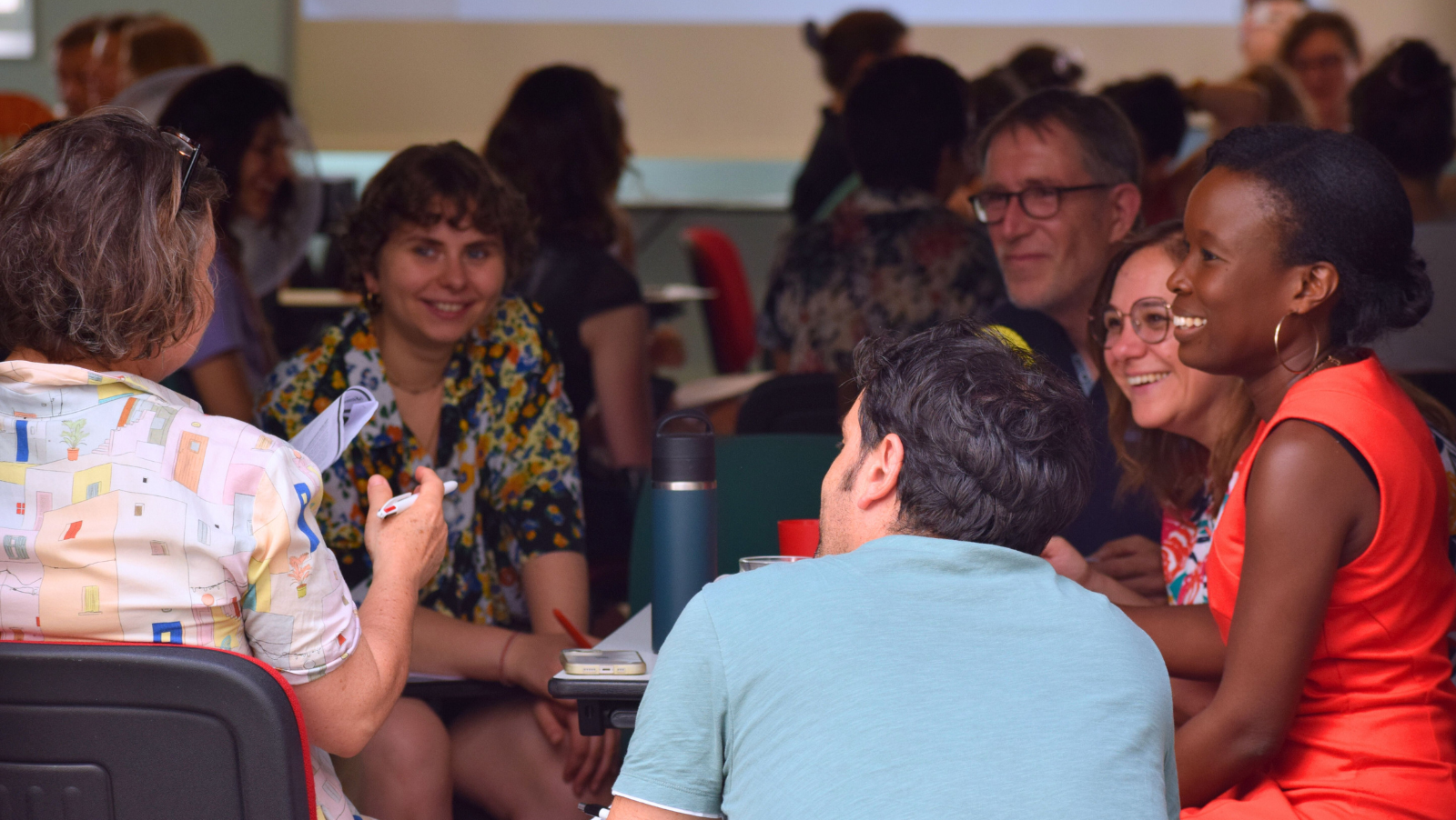 Un groupe d'adultes assis autour d'une table discute en souriant