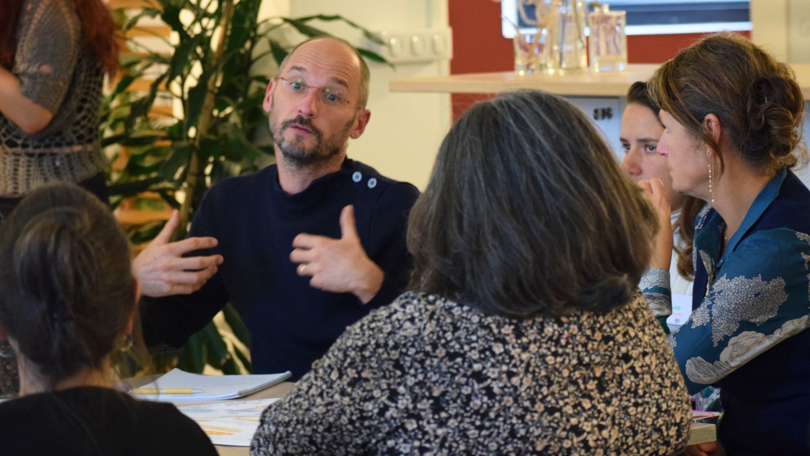 Un groupe d'adultes assis autour d'une table travail parle entre elles et eux