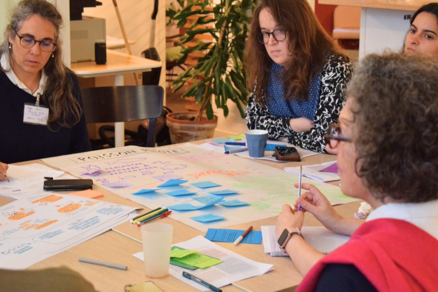 Un groupe d'adultes assis autour d'une table de travail, avec des post-it dispersés dessus