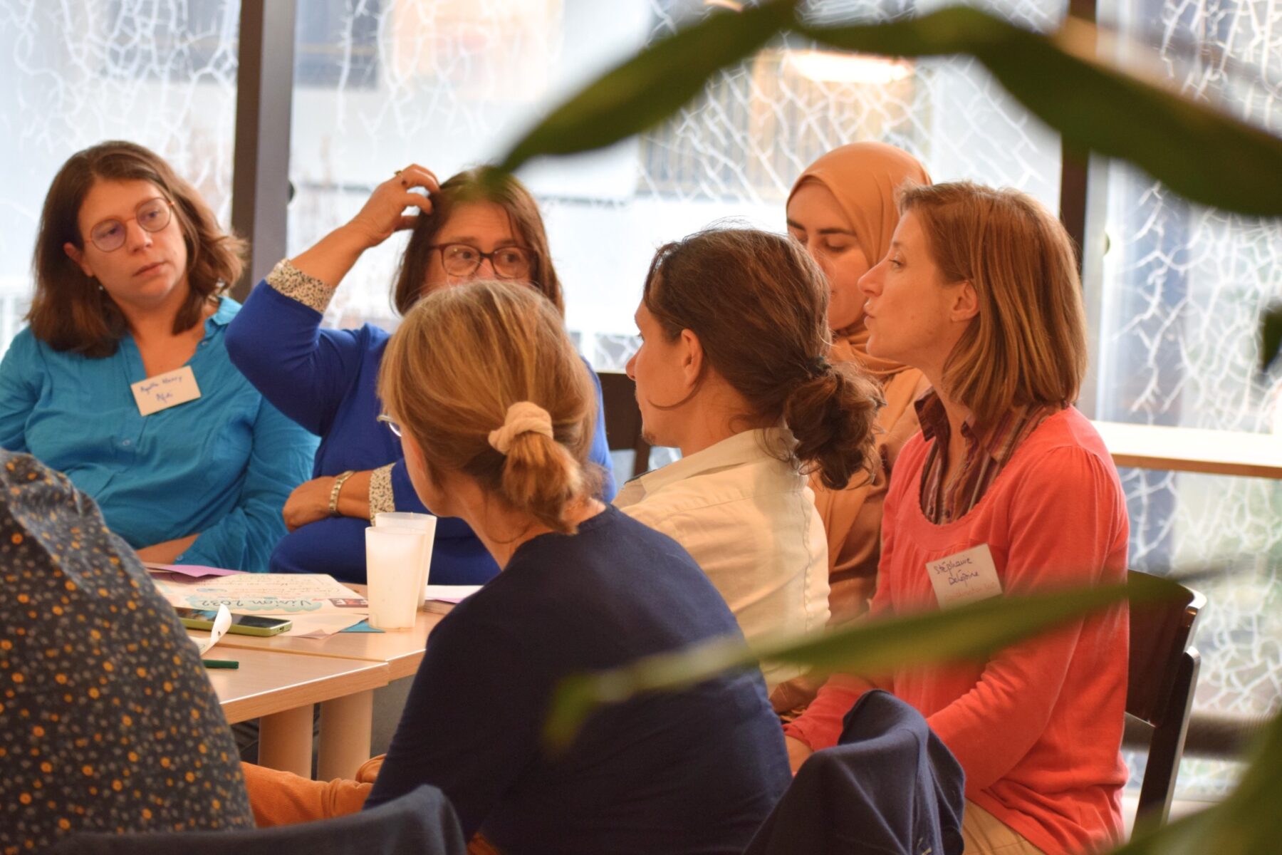 Un groupe d'adultes assis autour d'une table de travail, parle et échange entre elles et eux