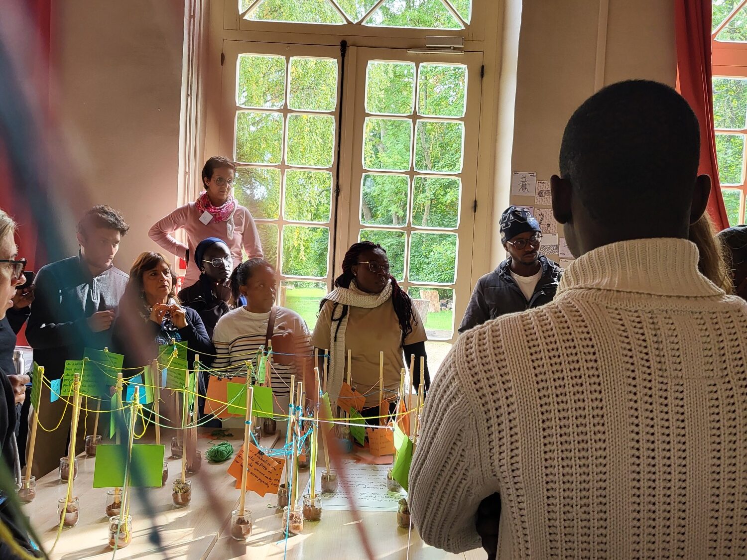 Un groupe d'adulte dans une pièce ensoleillé parle et échangent autour d'une table de travail