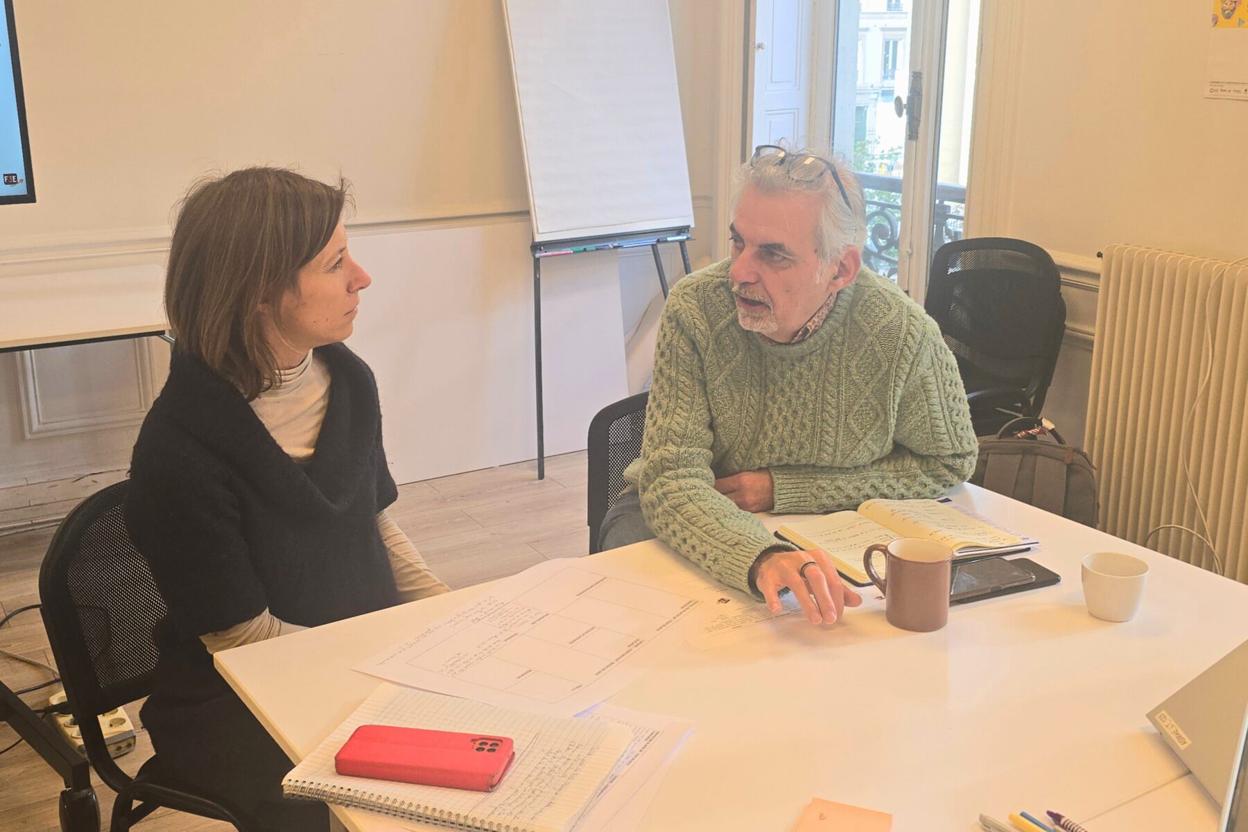 Deux adultes autour d'une table de travail parlent et échangent ensemble