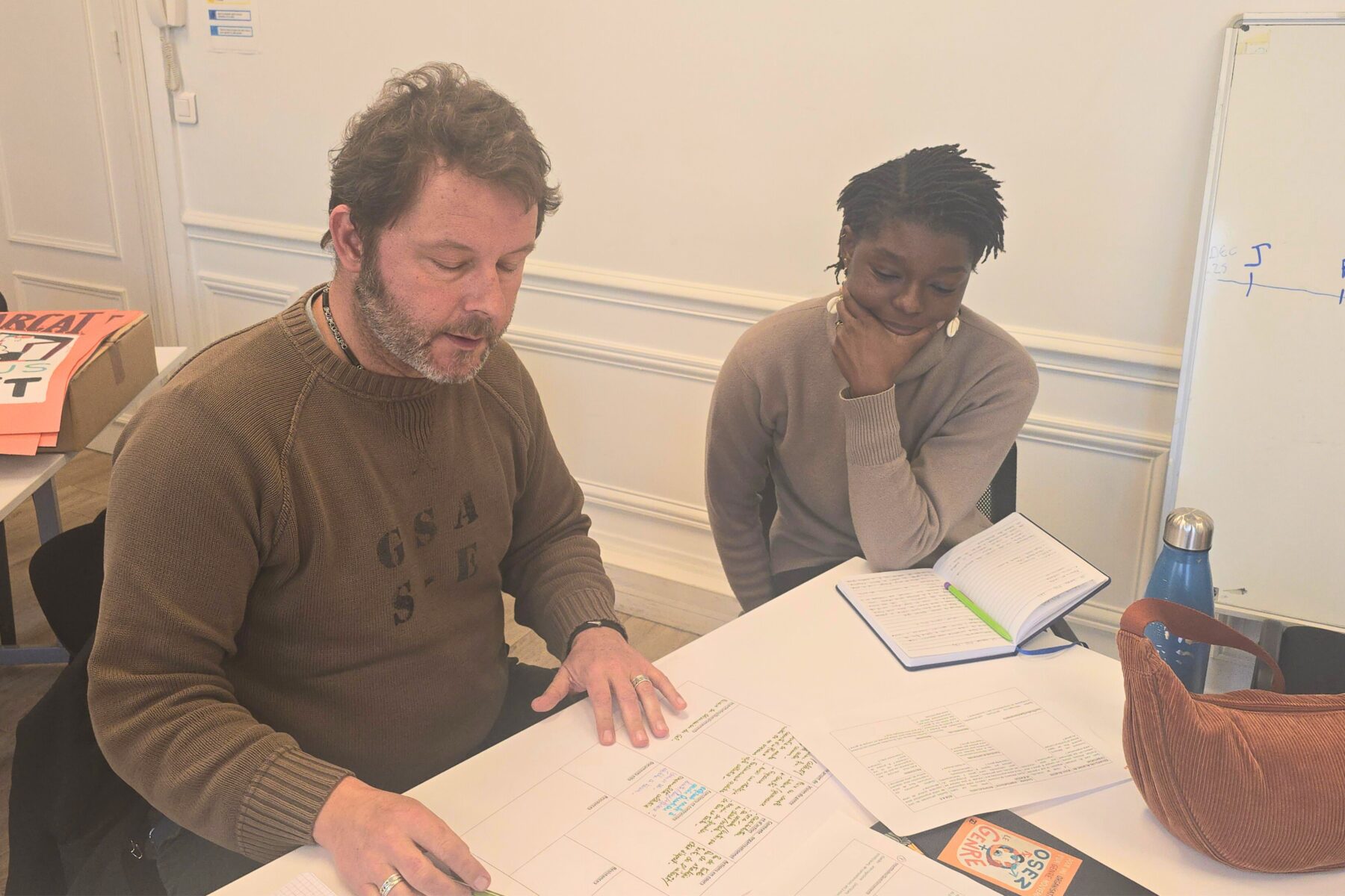 Deux adultes autour d'une table de travail parlent et échangent ensemble