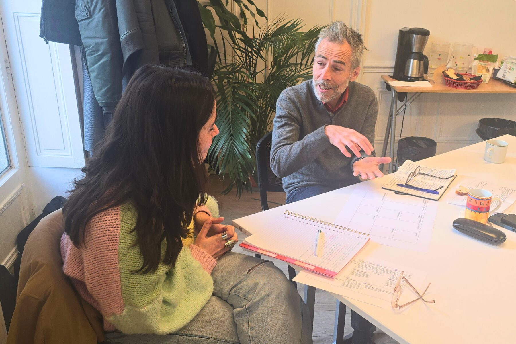 Deux adultes autour d'une table de travail parlent et échangent ensemble