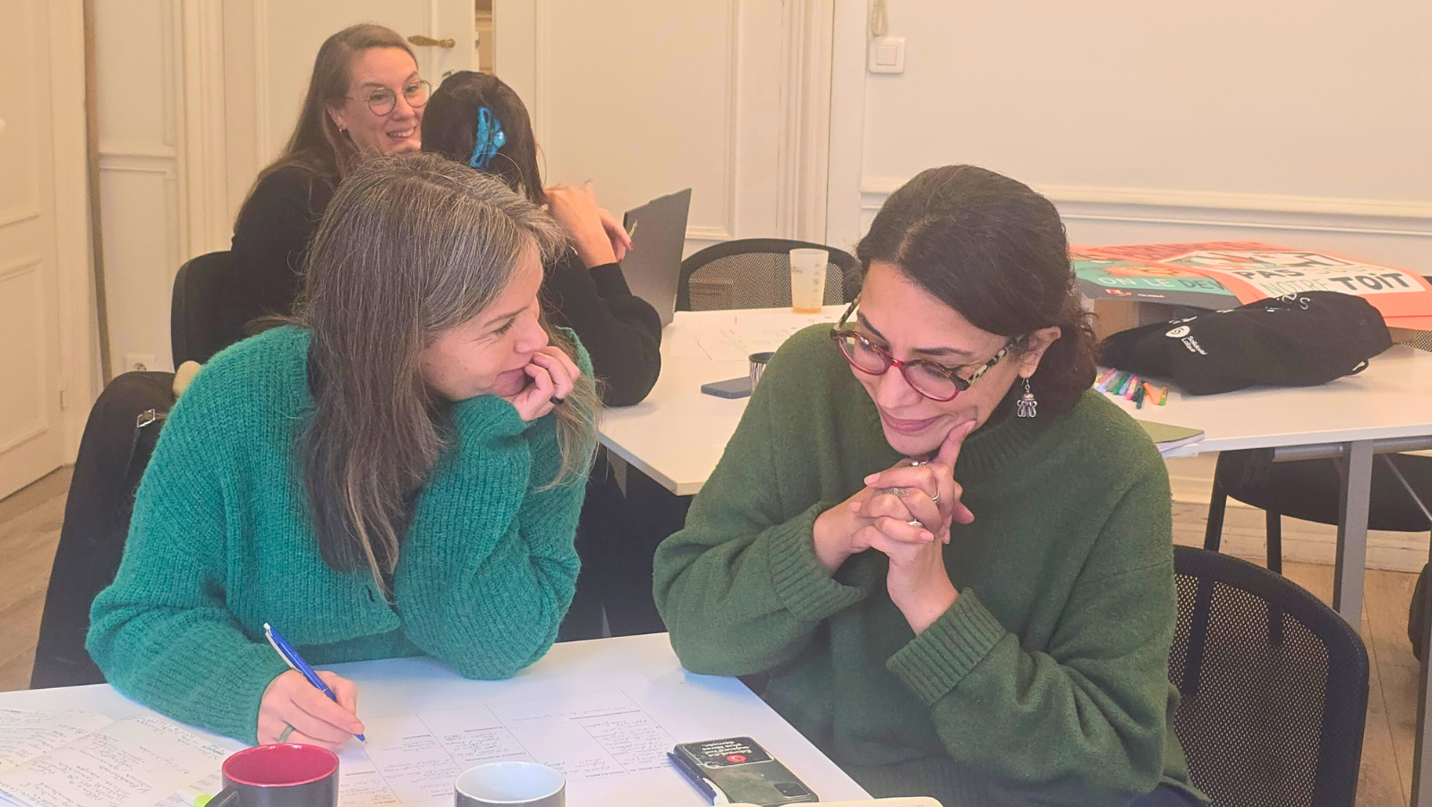 Deux adultes parlent et travaillent autor d'une table