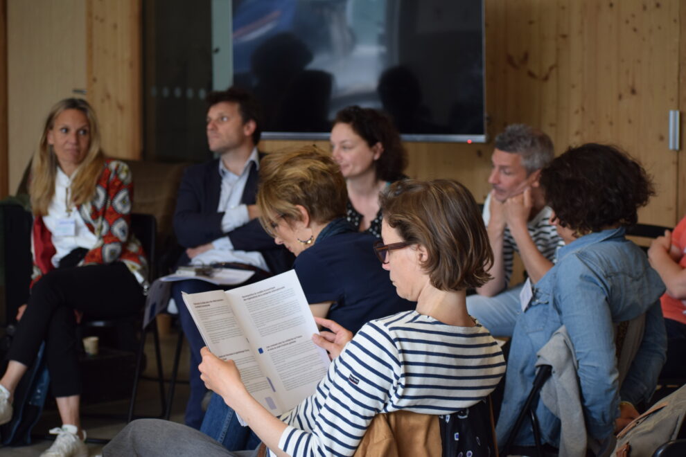 Groupe de parole en arrière plan et en premier plan une personne qui lit un dépliant