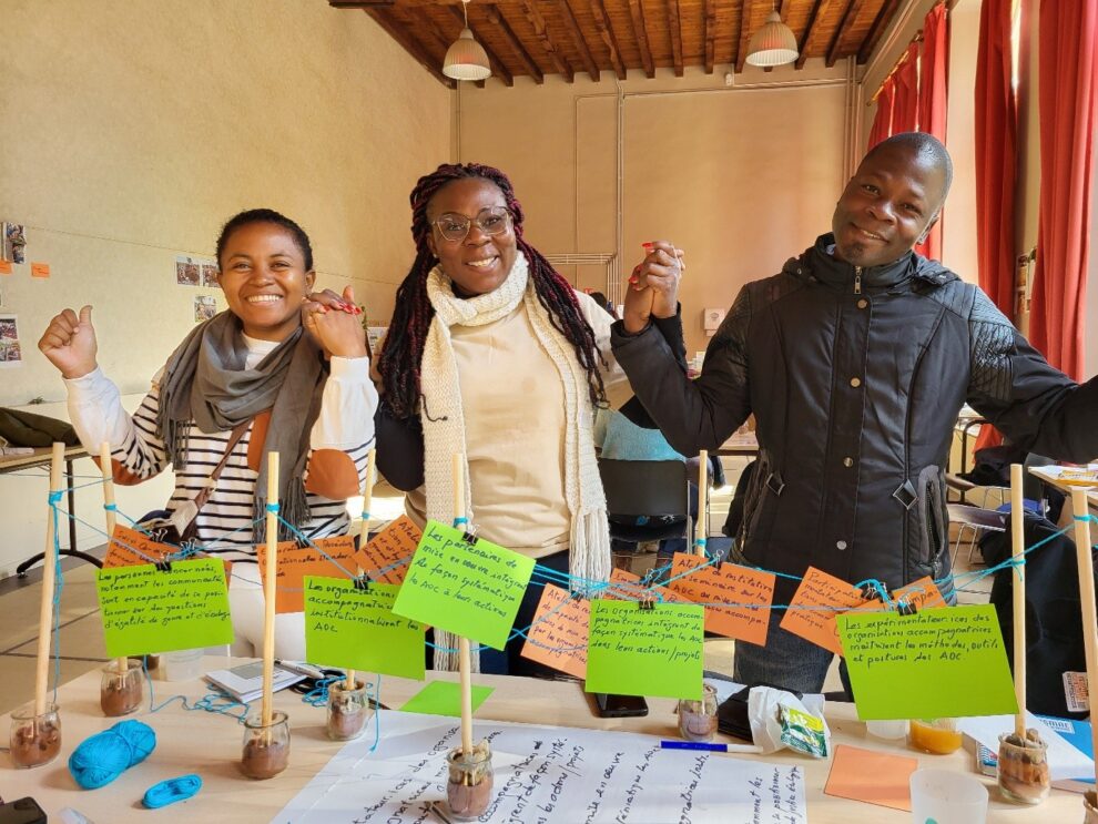Trois personnes se tenant par la main avec devant eux des maquettes issues d'un des webinaires collectifs